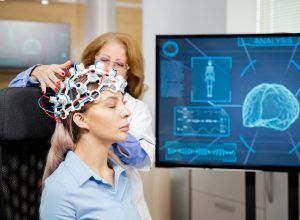 Doctor arranging scanning device on head of a female patient.