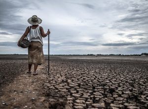 Women standing on dry soil and fishing gear, global warming and water crisis